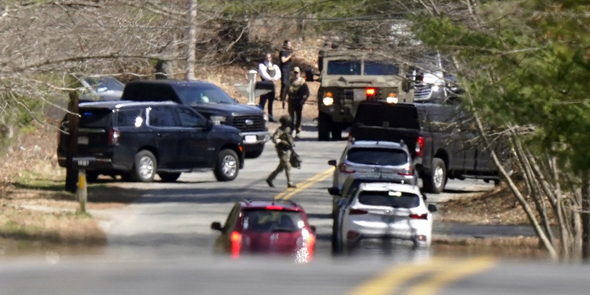 Members of law enforcement assemble on a road, Thursday, April 13, 2023, in Dighton, Mass., near where FBI agents converged on the home of a Massachusetts Air National Guard member who has emerged as a main person of interest in the disclosure of highly classified military documents on the Ukraine. The guardsman was identified as 21-year-old Jack Teixeira. (AP Photo/Steven Senne)