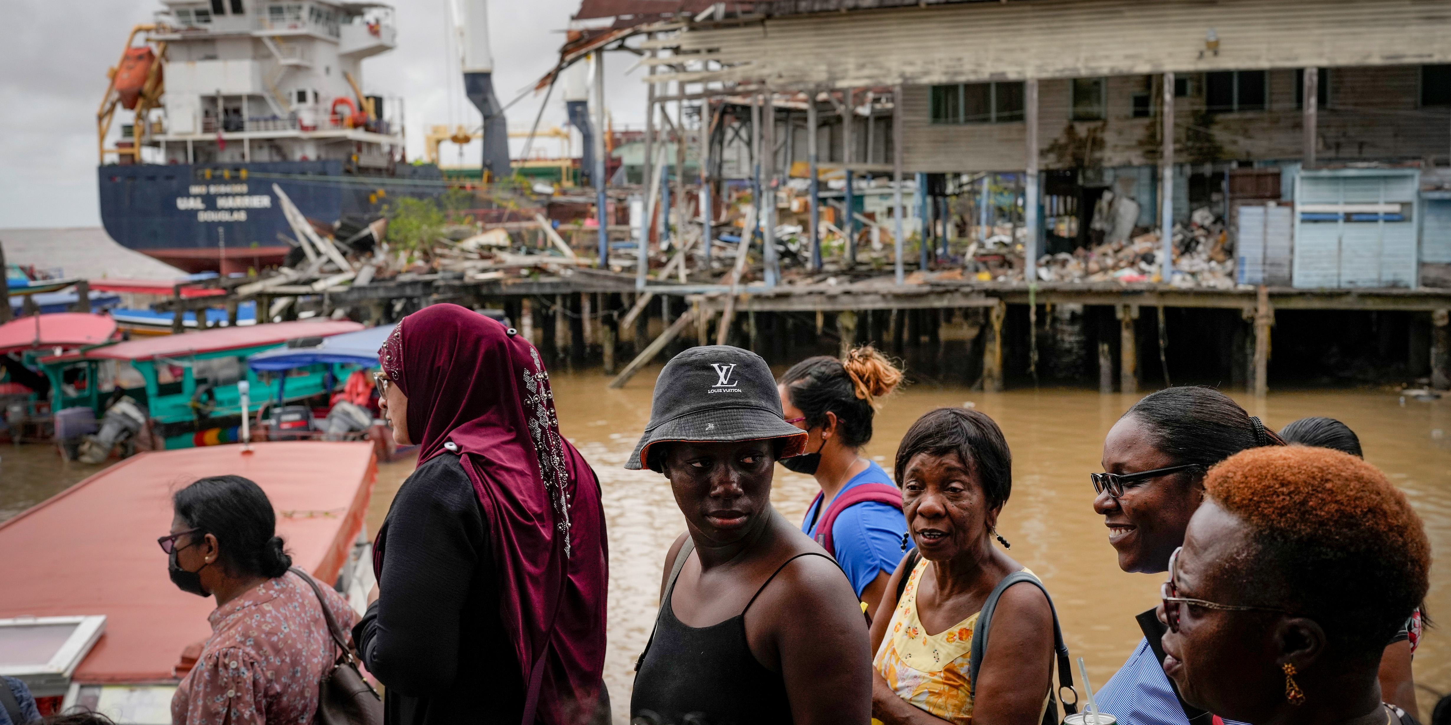 People wait at the Stabroek Market to ferry across the Demerara River, near a container ship in Georgetown, Guyana, Wednesday, April 12, 2023.  Guayana is poised to become the world’s fourth-largest offshore oil producer, placing it ahead of Qatar, the United States, Mexico and Norway.  (AP Photo/Matias Delacroix)