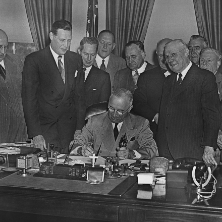 Pres. Harry Truman, seated at center, signs legislation raising the minimum wage from 40 to 75 cents, Oct. 26, 1949, Washington, D.C.