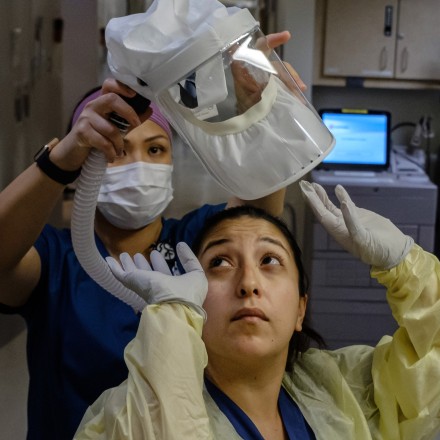 A nurse gets help putting on her personal protective equipment before administering care for a Covid-19 patient at Sharp Chula Vista Medical Center in Chula Vista, Calif., on April 10, 2020.