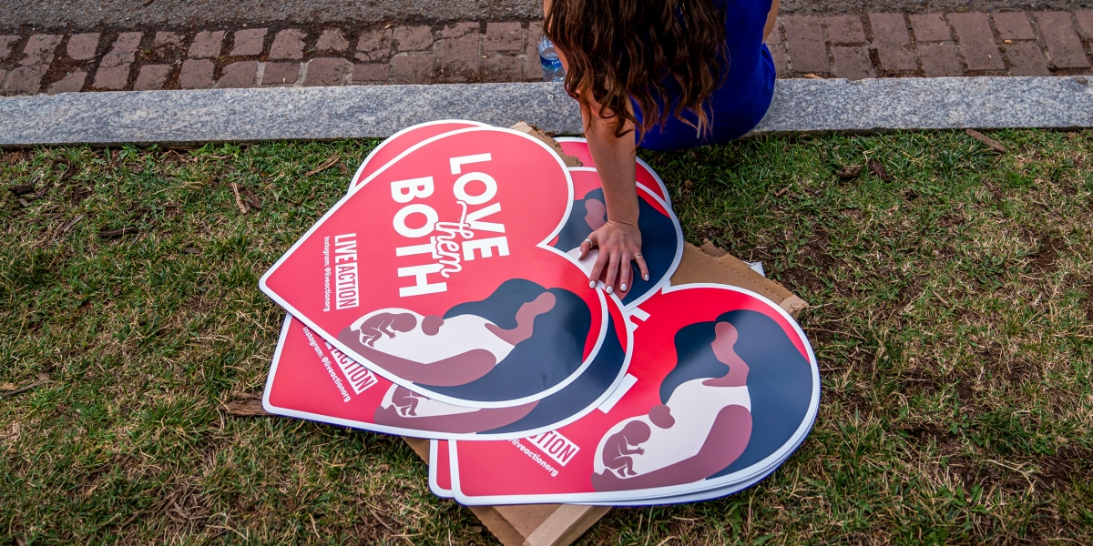 A woman rests next to anti-abortion posters in front of the U.S. Supreme Court after the Court announced a ruling in the Dobbs v Jackson Women's Health Organization case on June 24, 2022 in Washington, DC. The Court's decision in the Dobbs v Jackson Women's Health case overturns the landmark 50-year-old Roe v Wade case, removing a federal right to an abortion. (Photo by Nathan Howard/Getty Images)